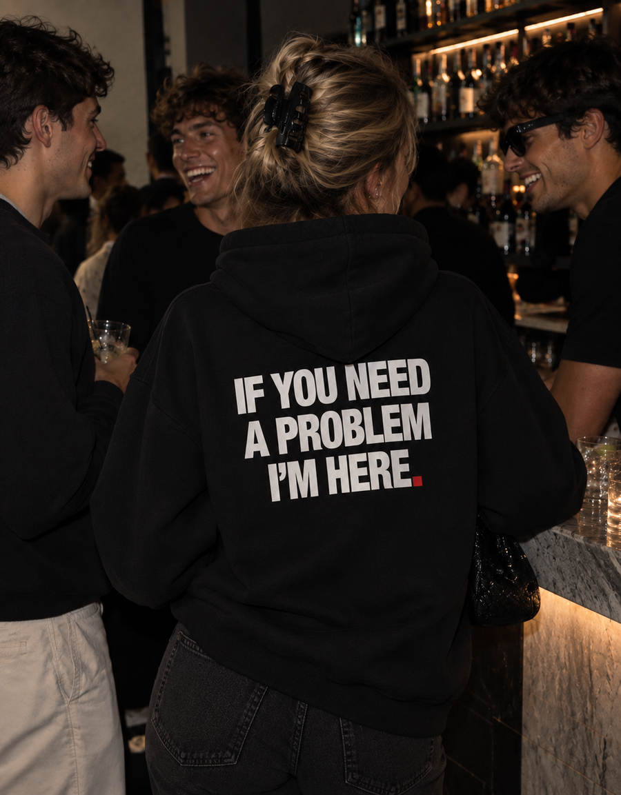 Color Black — OVRSAID IF YOU NEED A PROBLEM, I'M HERE. oversized hoodie on female model at a bar, back view showing the white back print
