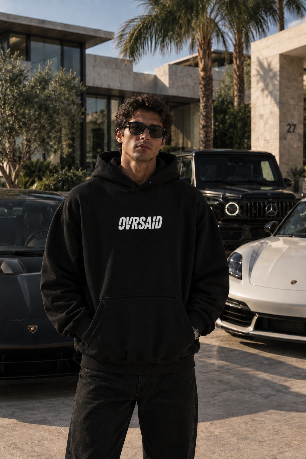 Color Black — OVRSAID ONE DAY THIS WILL ALL BE TAX DEDUCTIBLE. oversized hoodie on male model, front view with small OVRSAID chest mark