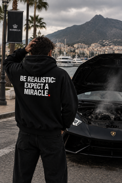 Color Black — OVRSAID BE REALISTIC: EXPECT A MIRACLE. oversized hoodie on male model, back view showing the white back print